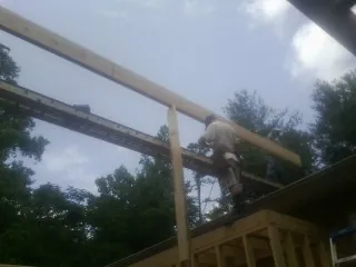 Carpenter setting a ridge beam over a new addition frame — Ice Dam Removal by Roofing Brothers in Pleasant Grove