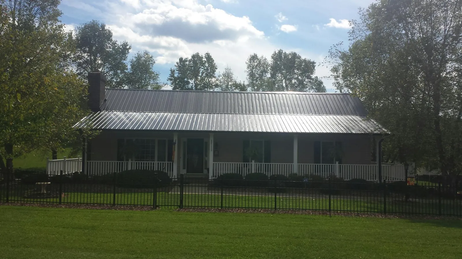 Gray metal roof on a brick ranch with a full width front porch — Gutter Guard Installation work by our crew in Pleasant Grove